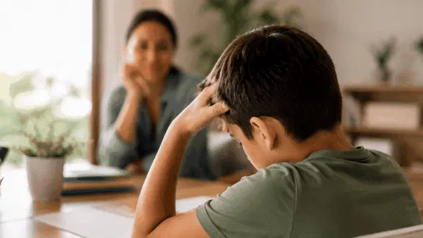 Child at school desk looking frustrated with schoolwork