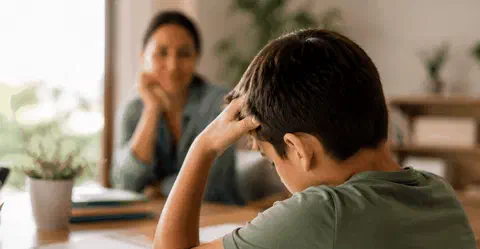 Child at school desk looking frustrated with schoolwork